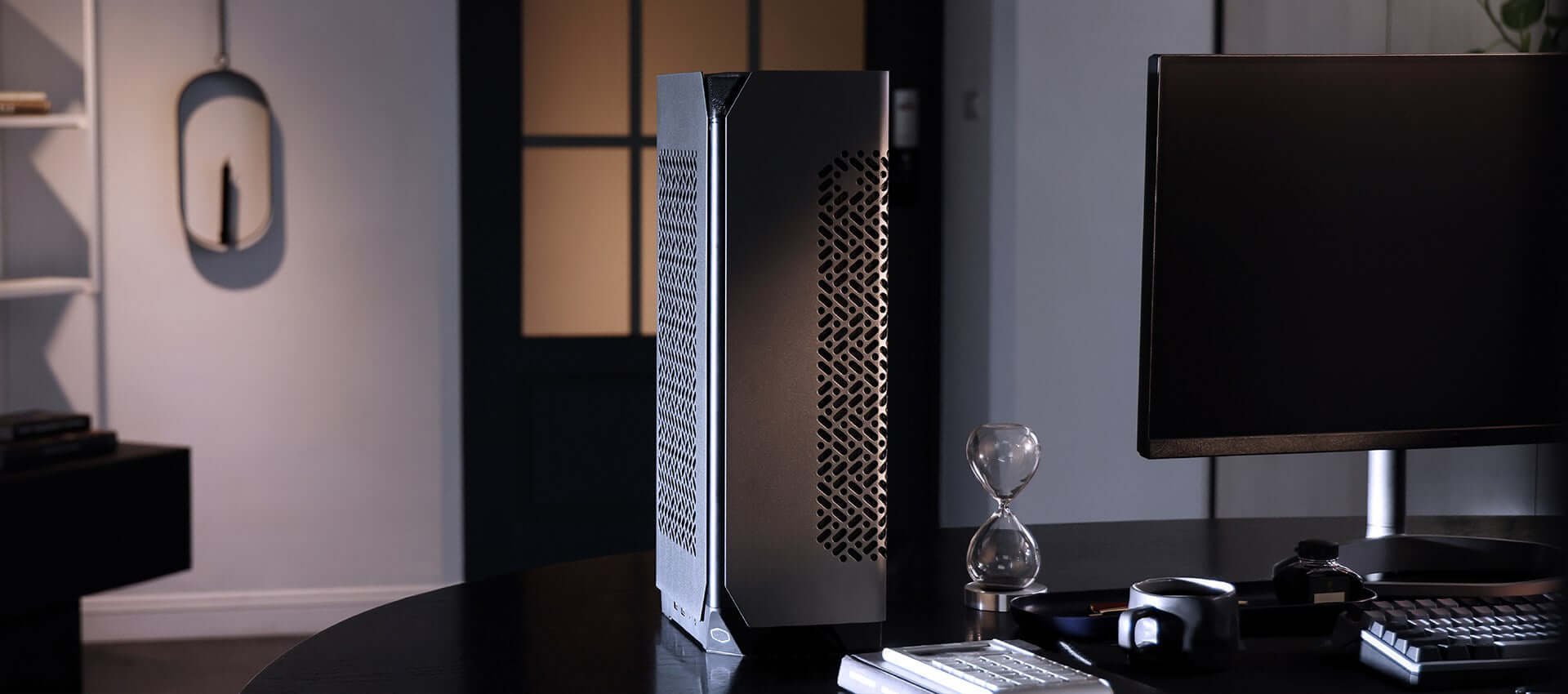 Modern minimalist computer setup with black desk, sleek PC tower, monitor, accessories, and decor in a stylish home office.